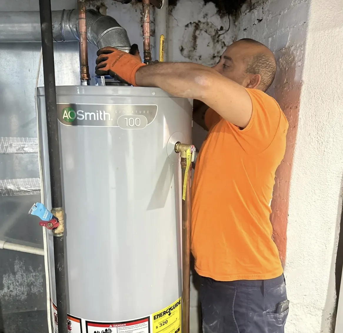 Plumber working on a gas water heater in a utility room